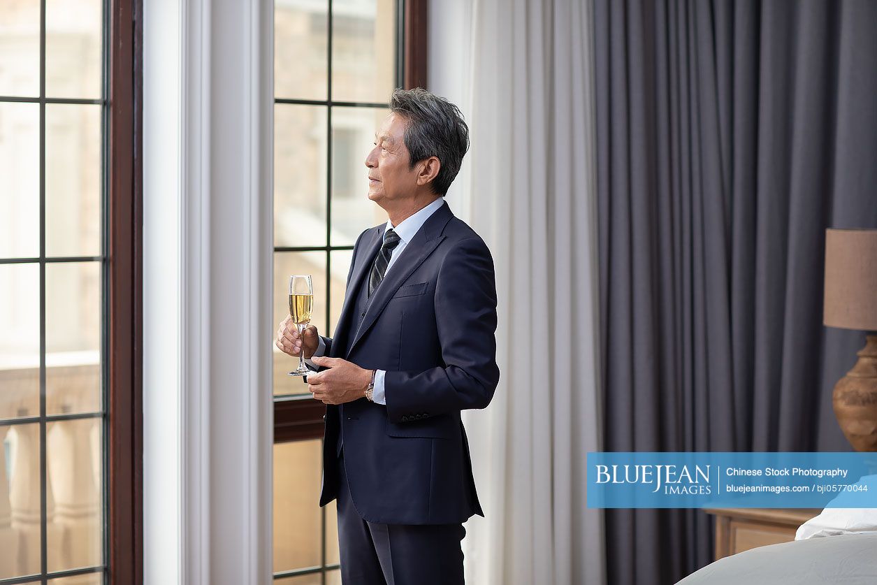 Senior Chinese man drinking champagne at home