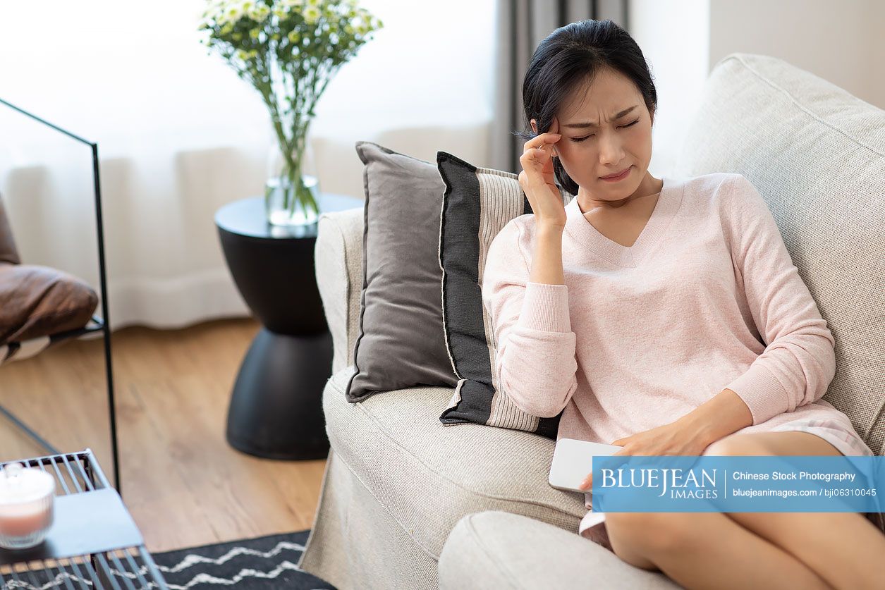 Young Chinese woman having a headache at home