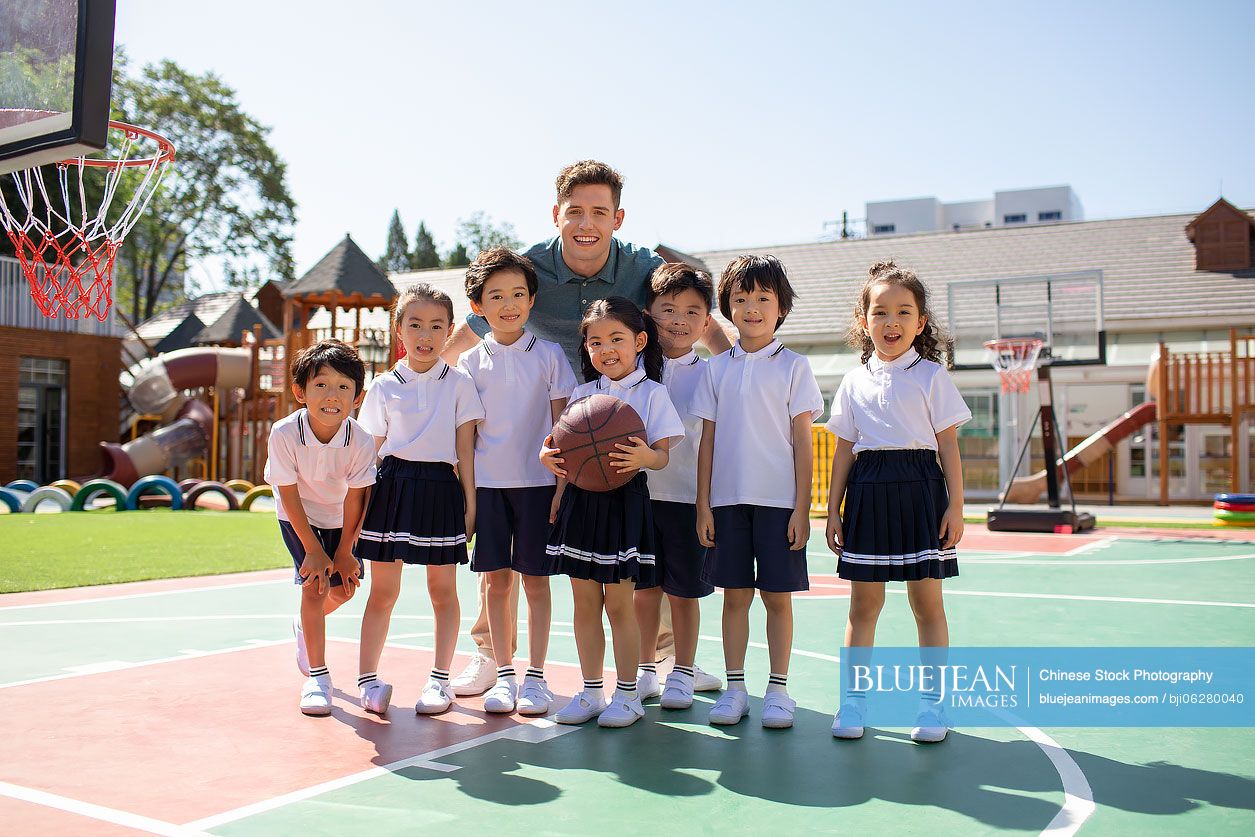 Foreign teacher and children playing basketball in playground