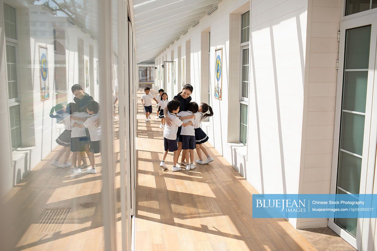 Chinese teacher and children in school hallway