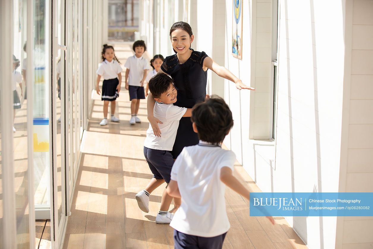 Chinese teacher and children in school hallway