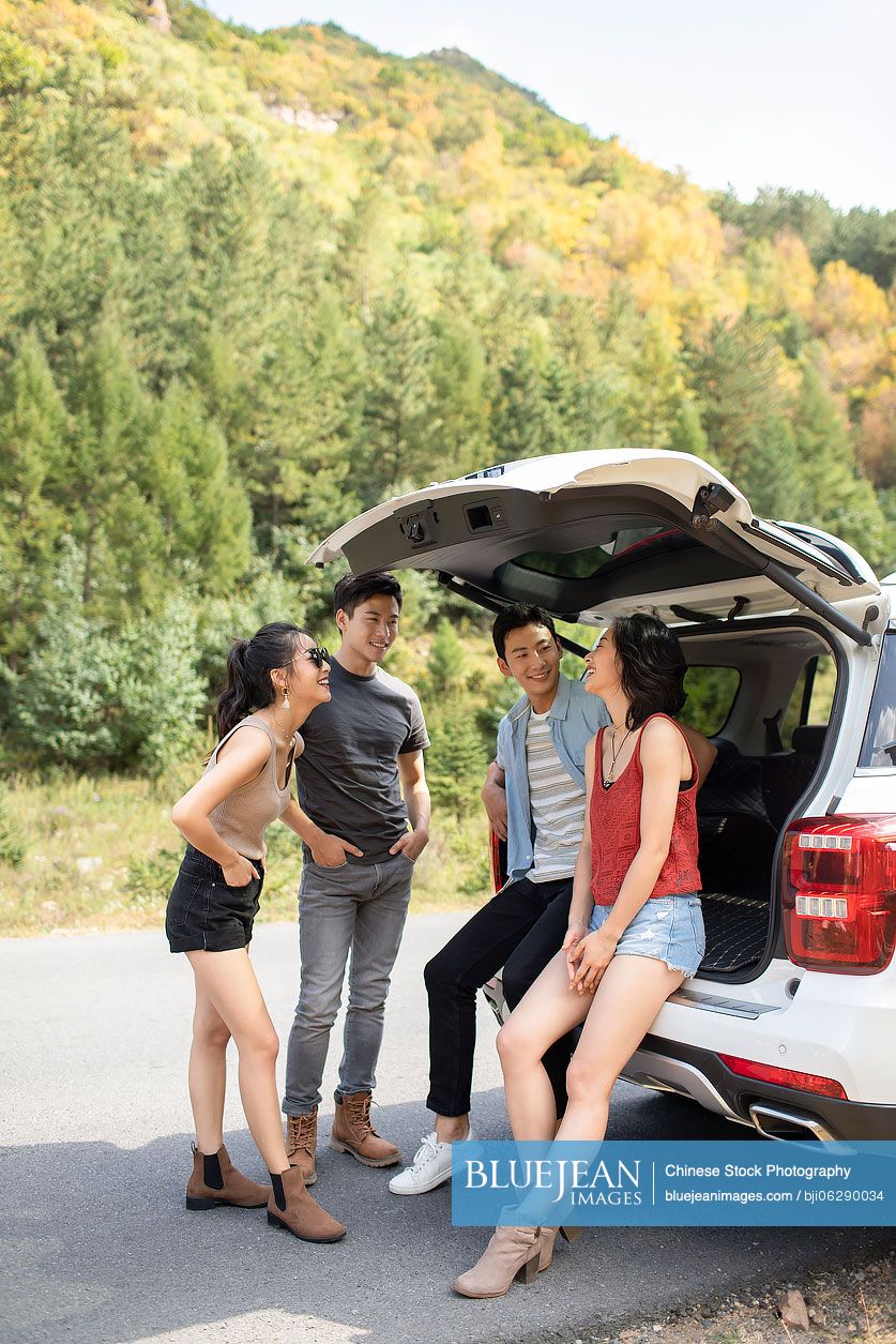 Happy young Chinese friends enjoying road trip