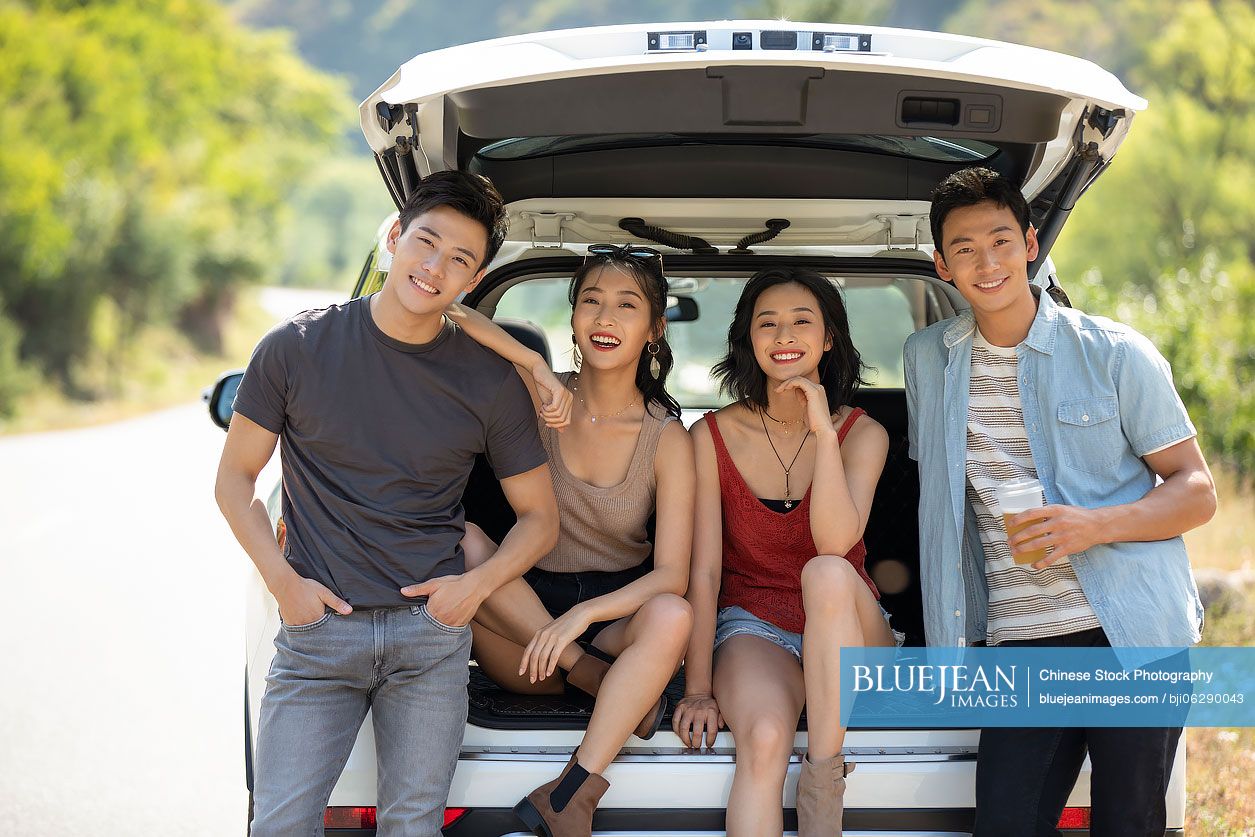 Happy young Chinese friends enjoying road trip
