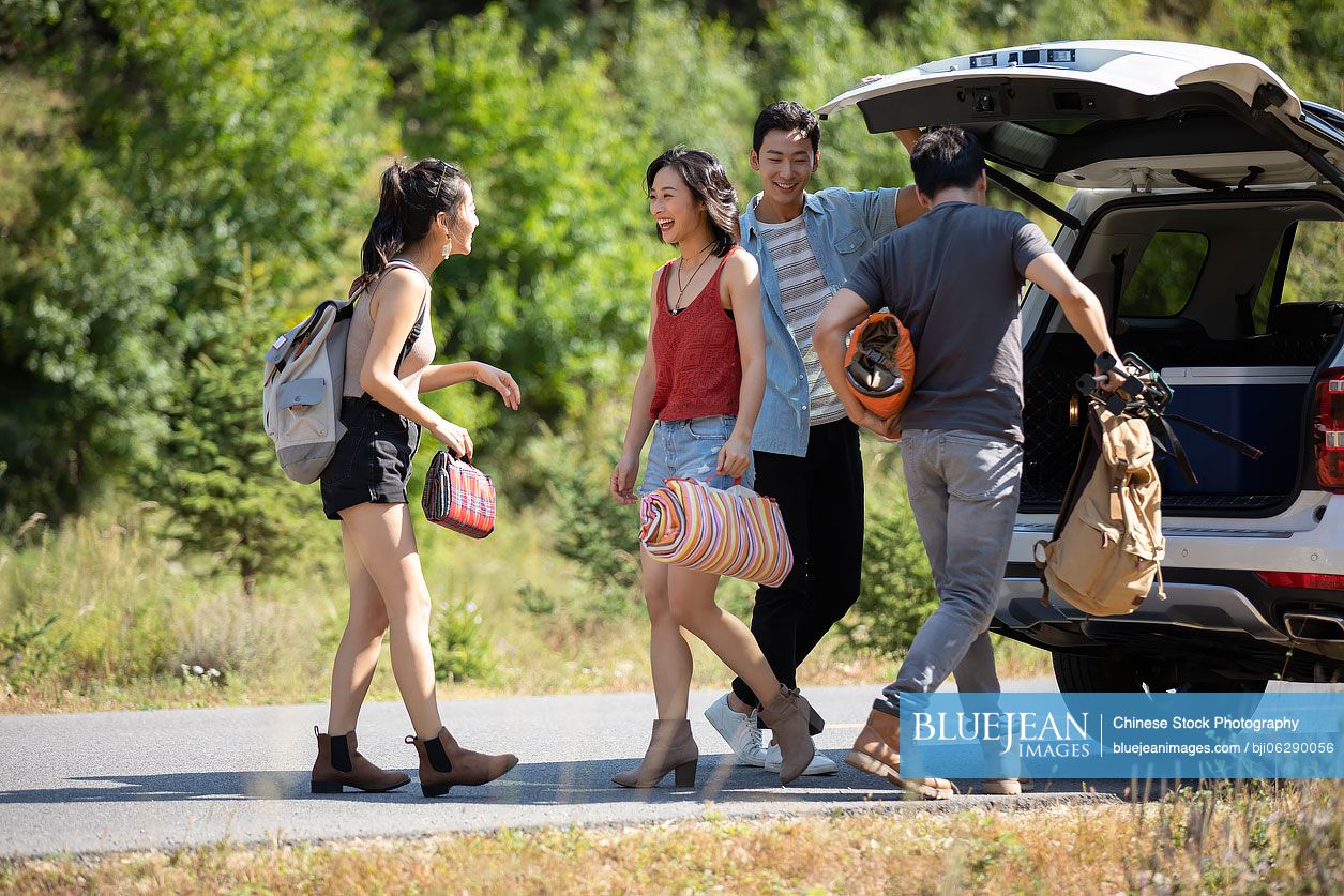 Happy young Chinese friends camping outdoors