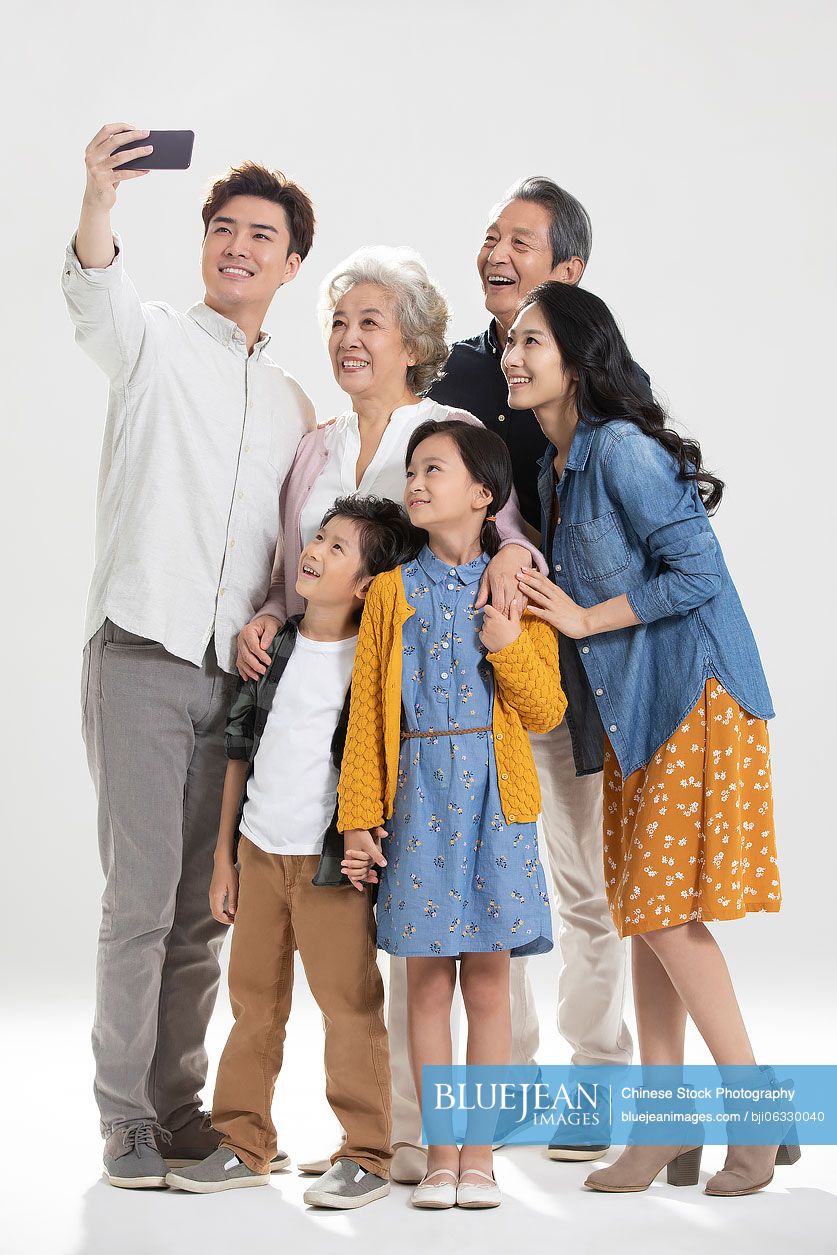 Happy Chinese family taking selfie with smartphone