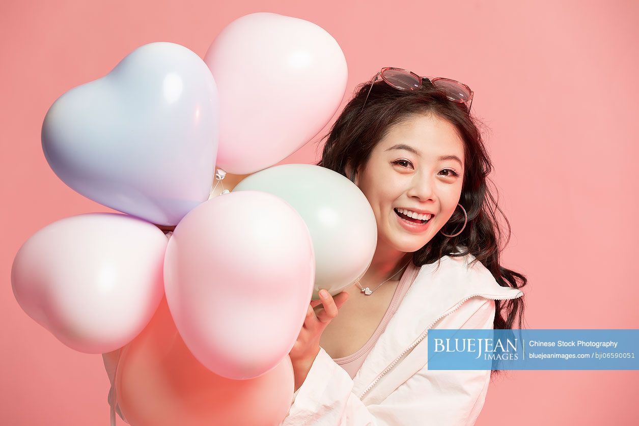 Studio shot of cute young Chinese woman with balloons