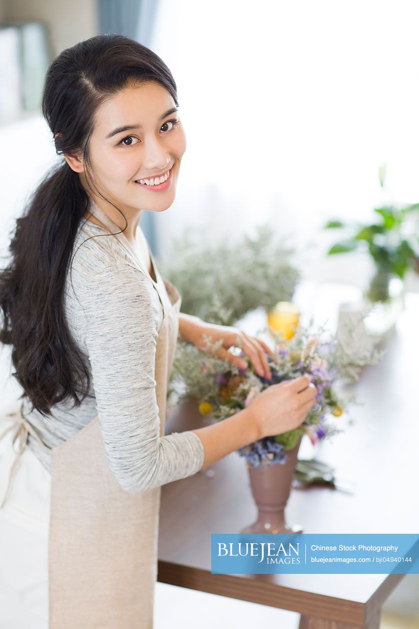 Young Chinese woman arranging flowers at home