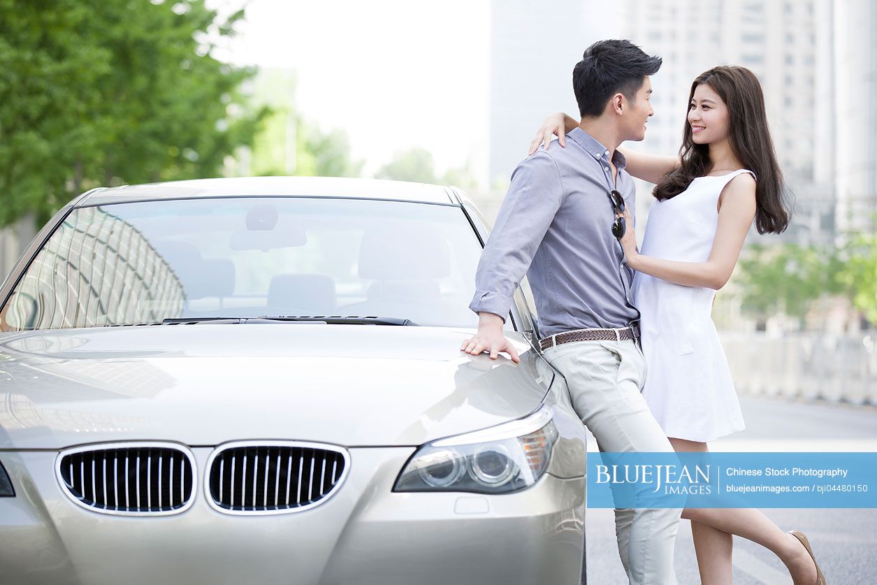 Happy young Chinese couple and car