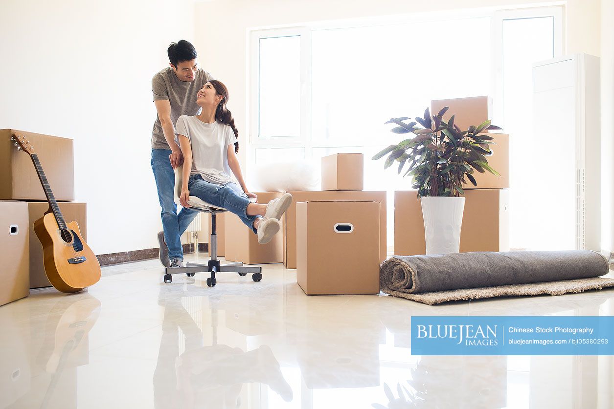 Happy young Chinese couple moving to a new house