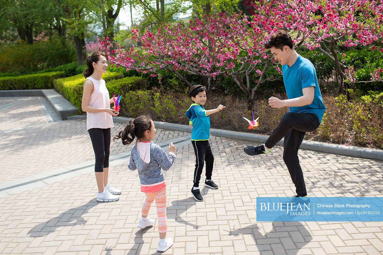Happy young Chinese family kicking shutterlock in park