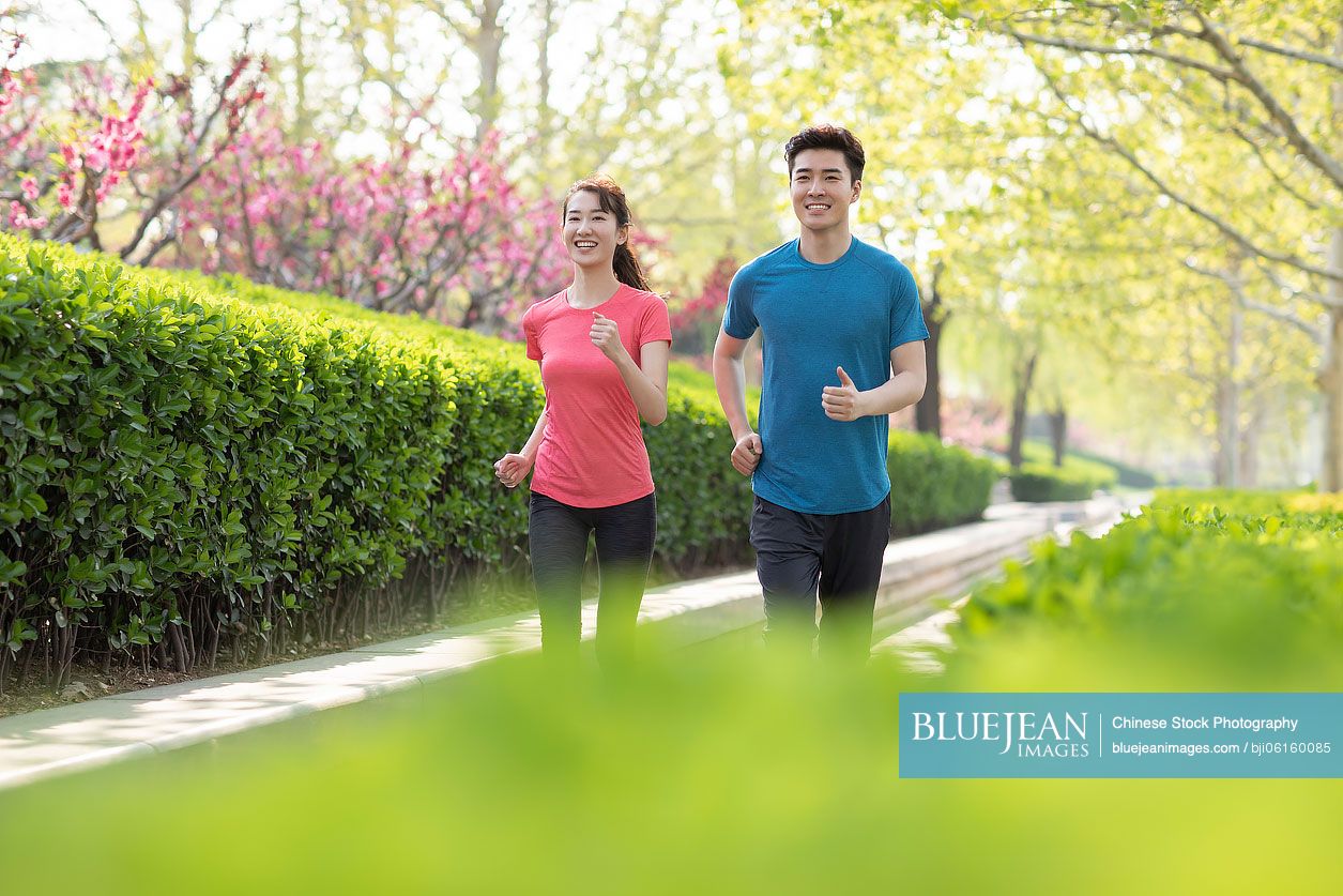 Happy young Chinese couple running in park