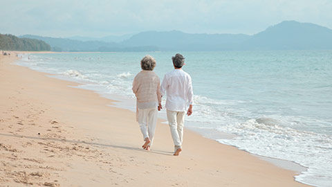 Happy senior Chinese couple walking on beach,4K