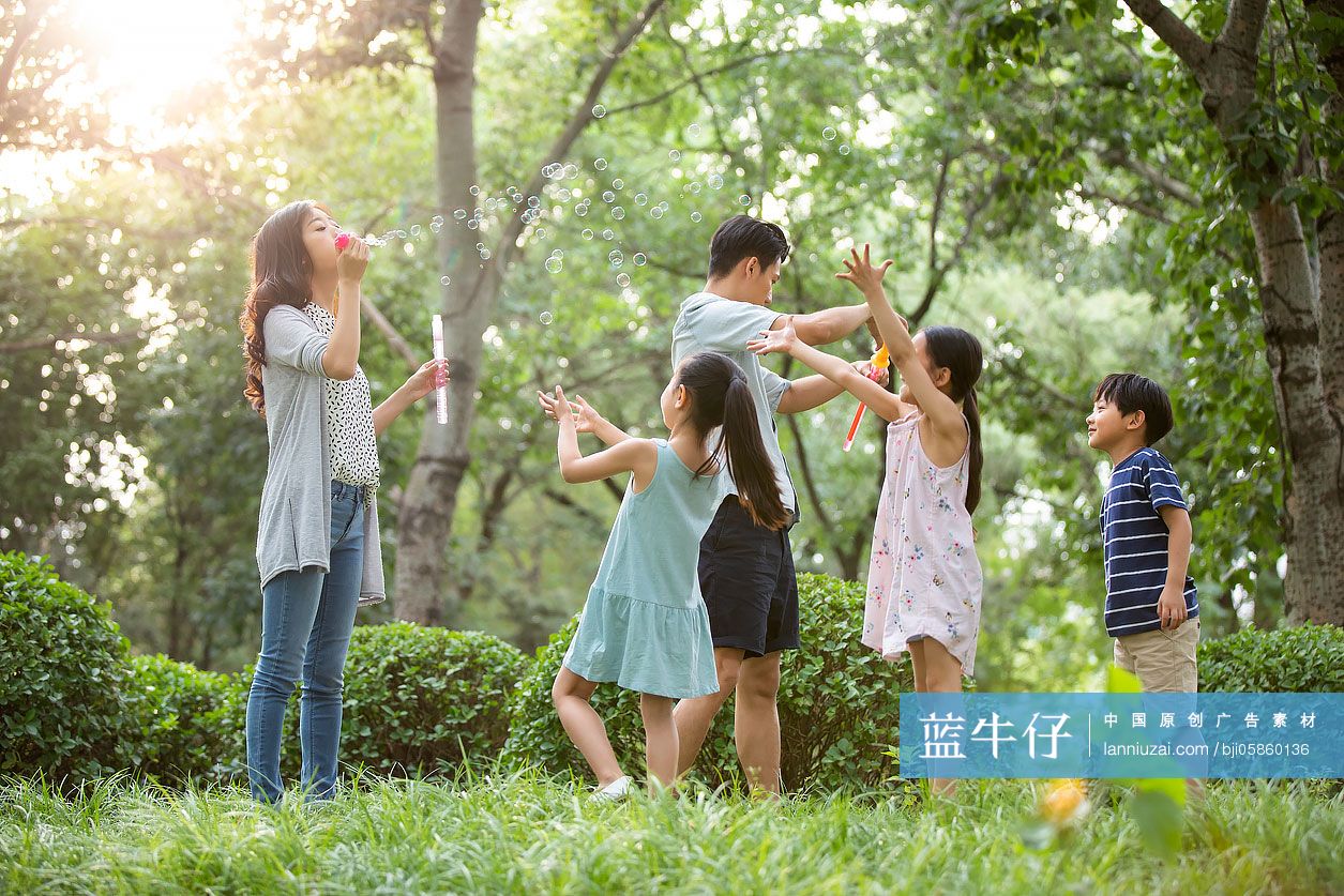 快乐年轻家庭在草地上吹泡泡