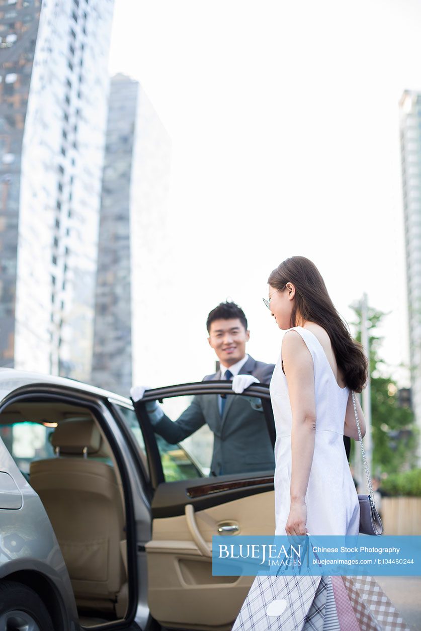 Chinese chauffeur opening car door for a young woman
