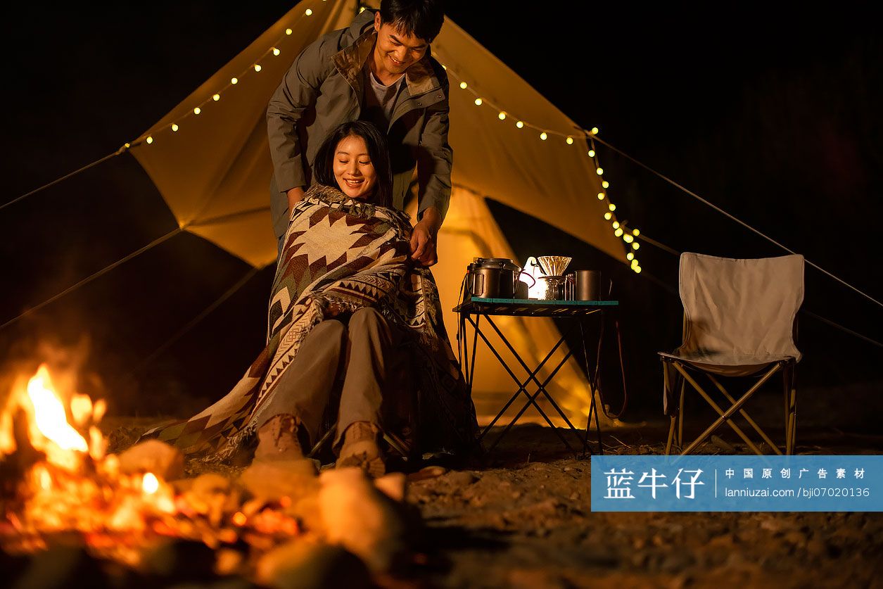 年轻情侣晚上在户外露营烤火