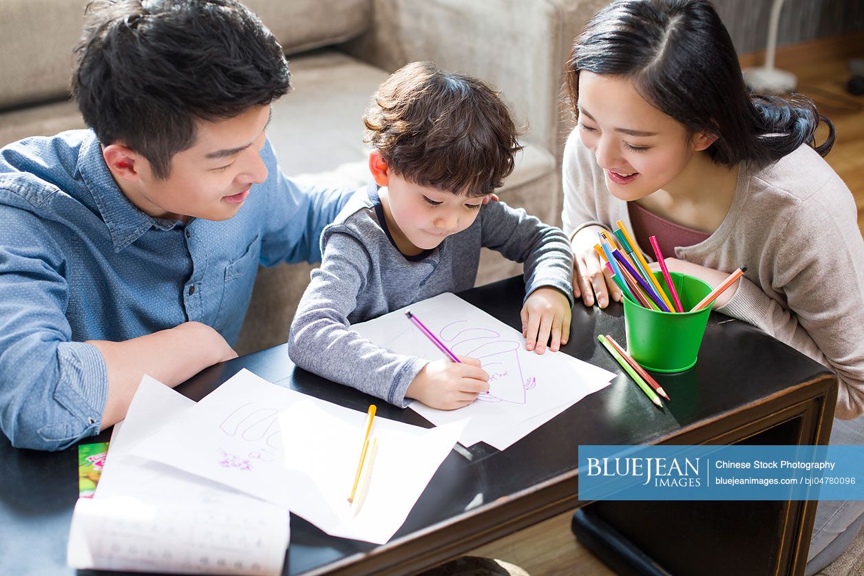 Young Chinese parents helping son with homework