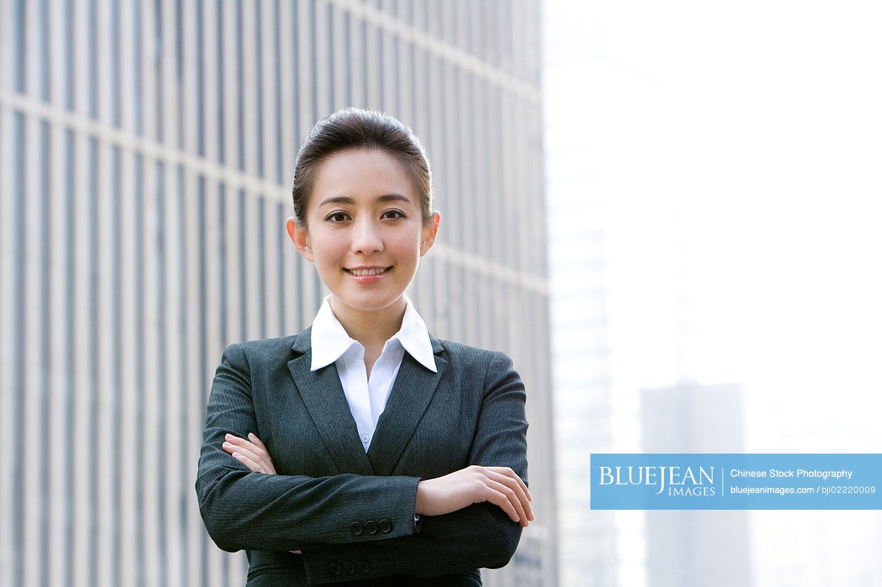 Confident Chinese businesswoman standing in front of downtown building