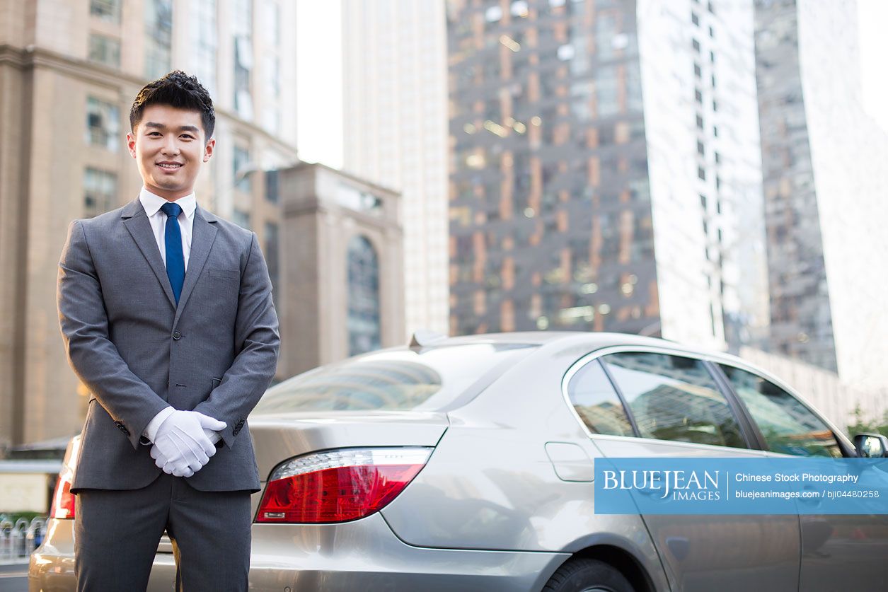Portrait of Chinese chauffeur standing next to the car