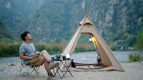 Happy young Chinese man camping outdoors