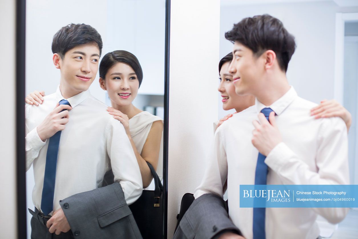 Young Chinese couple looking into a mirror before going to work