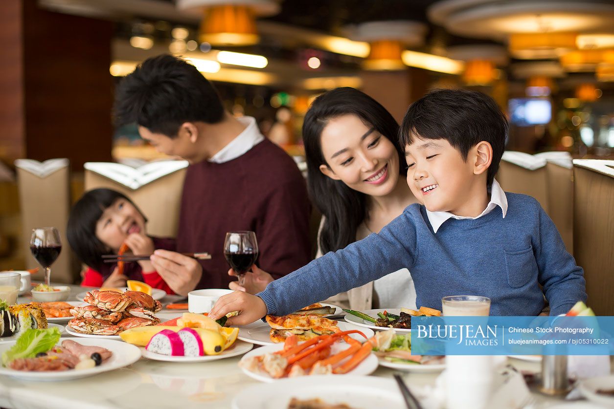 Cheerful young Chinese family having buffet dinner