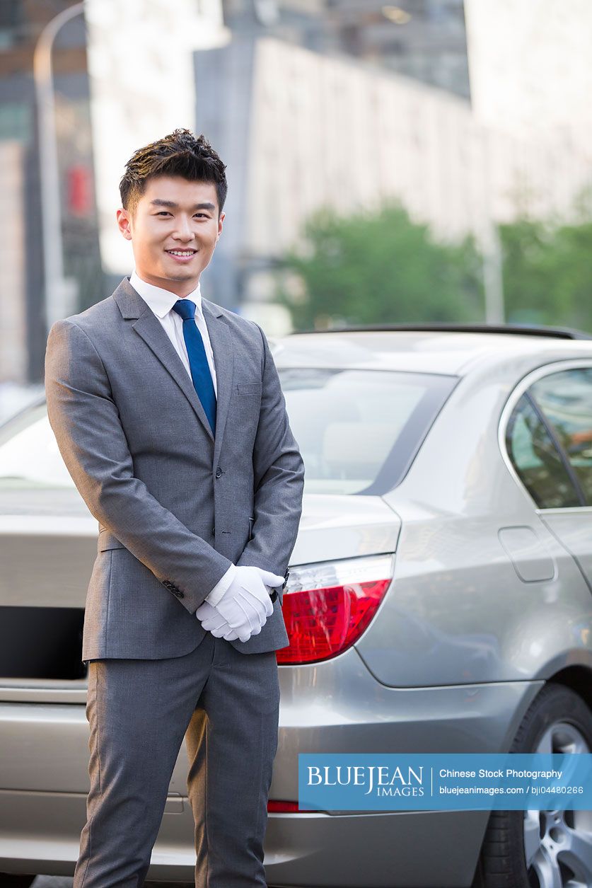 Portrait of Chinese chauffeur standing next to the car