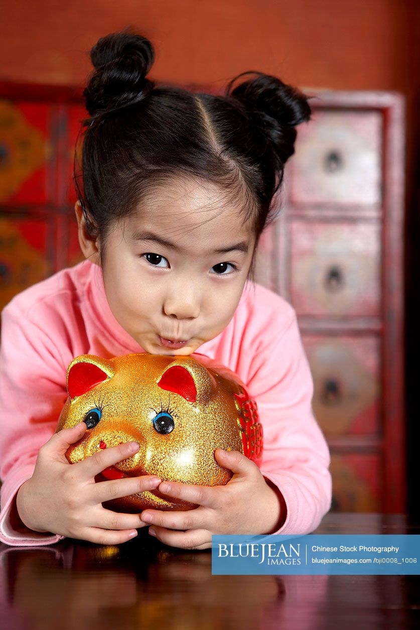Chinese girl kissing piggy bank
