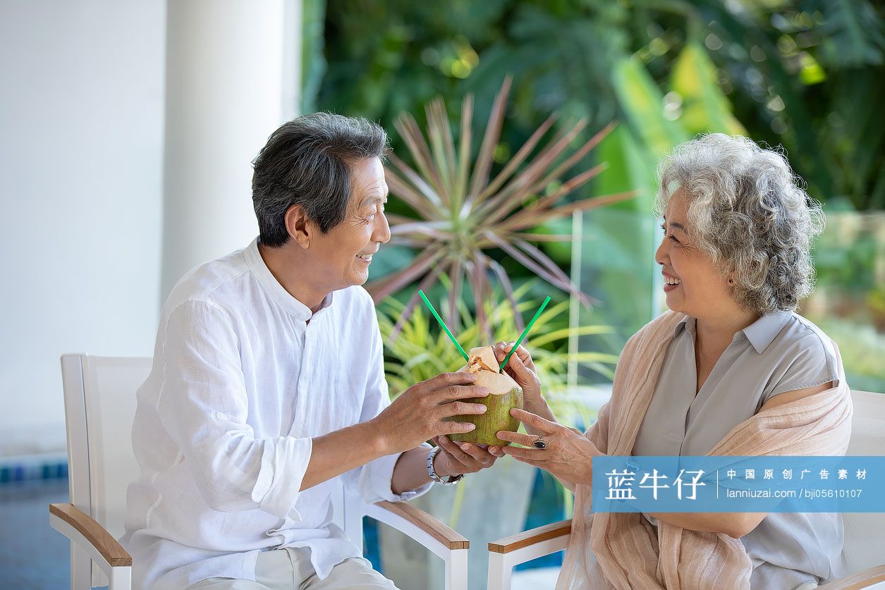 快乐的老年夫妇在阳台喝椰汁