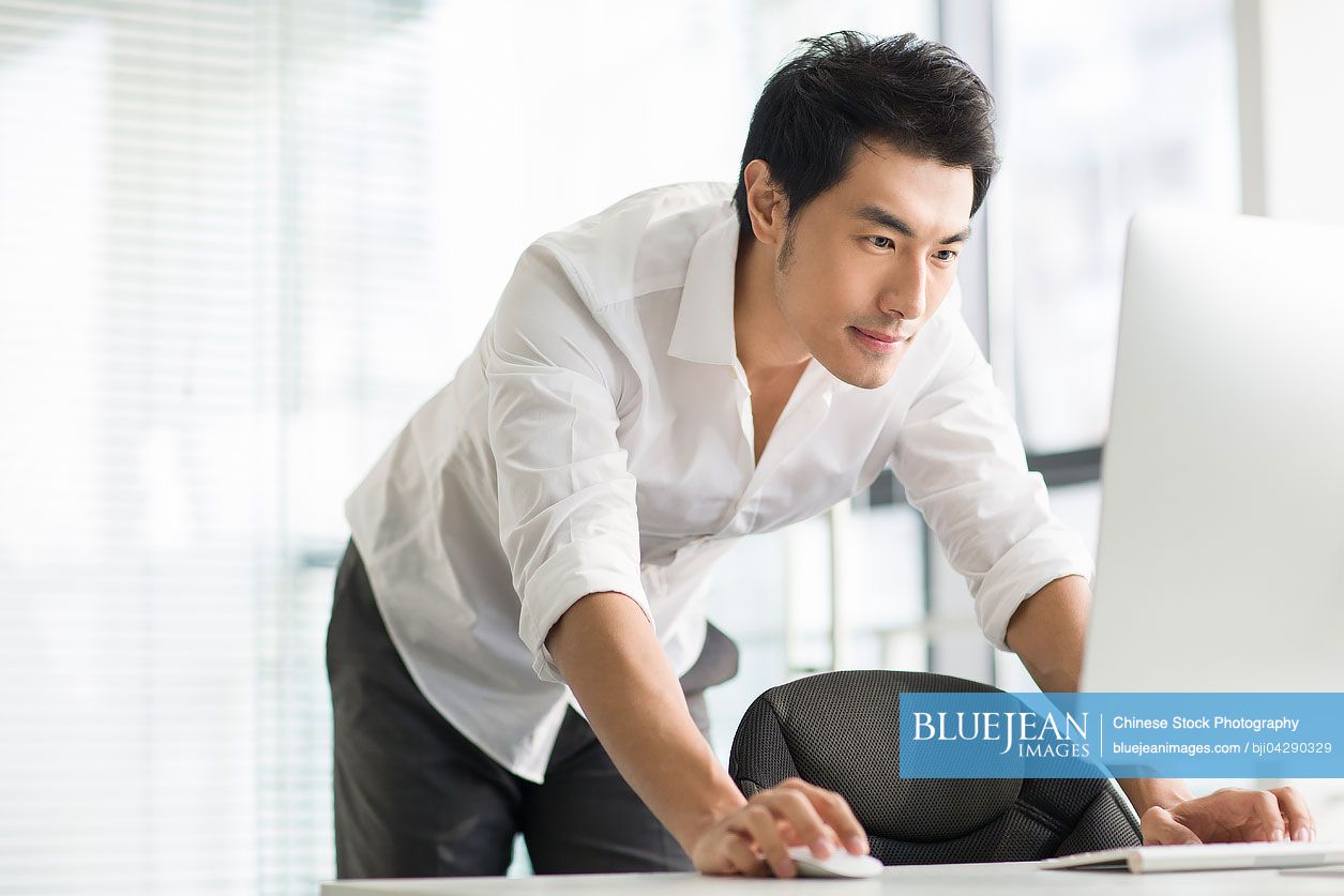 Young Chinese businessman using computer in office