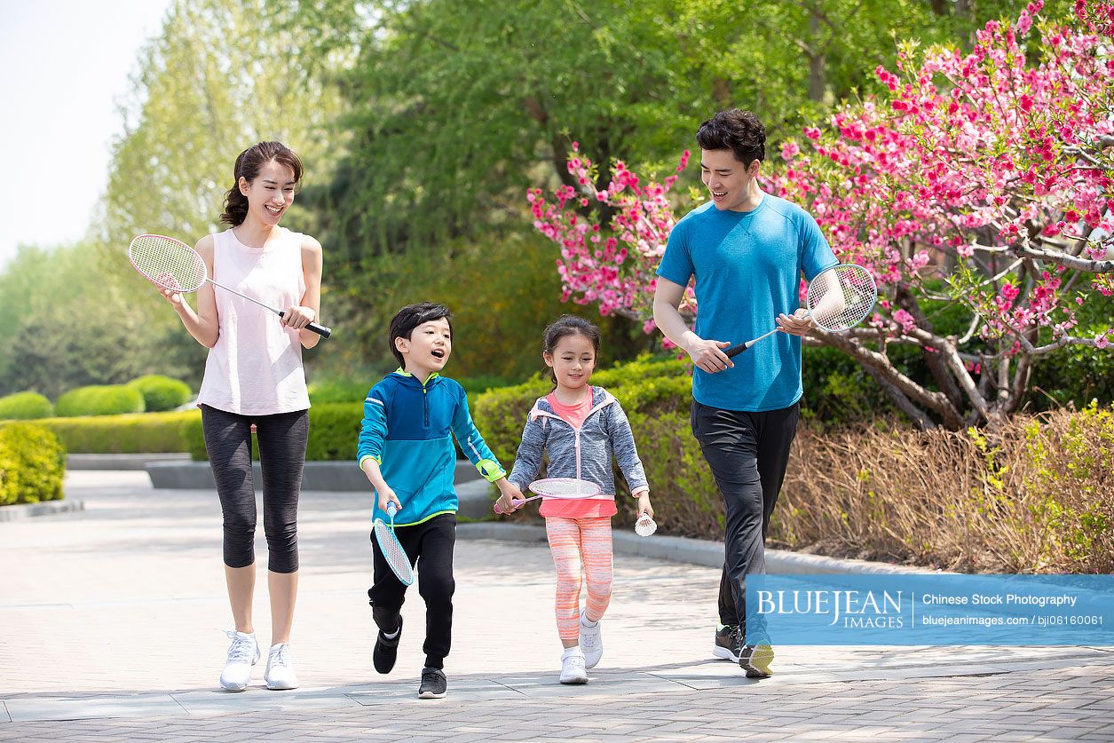 Happy young Chinese family playing badminton in park