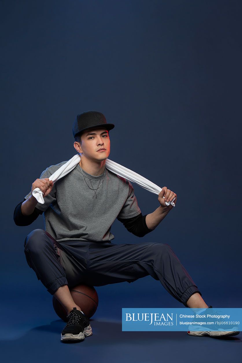 Studio shot of fashionable young Chinese man with basketball