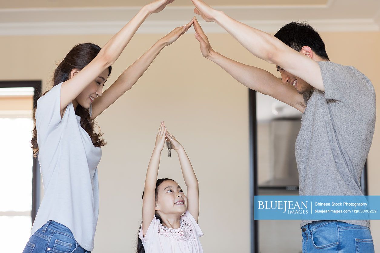 Happy young Chinese family holding keys in their new house