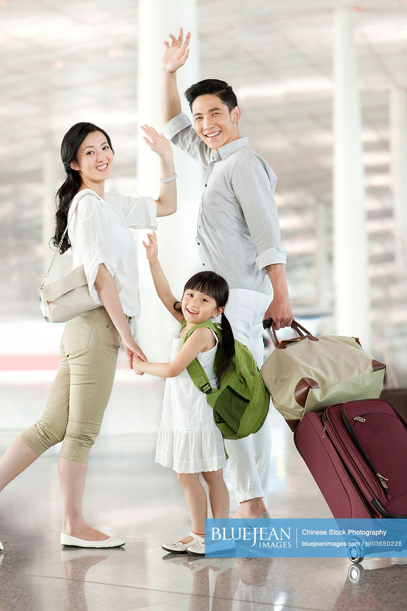 Young Chinese family waving goodbye at the airport