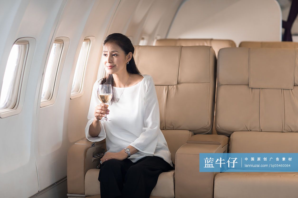 优雅的中年女士在机舱里喝葡萄酒