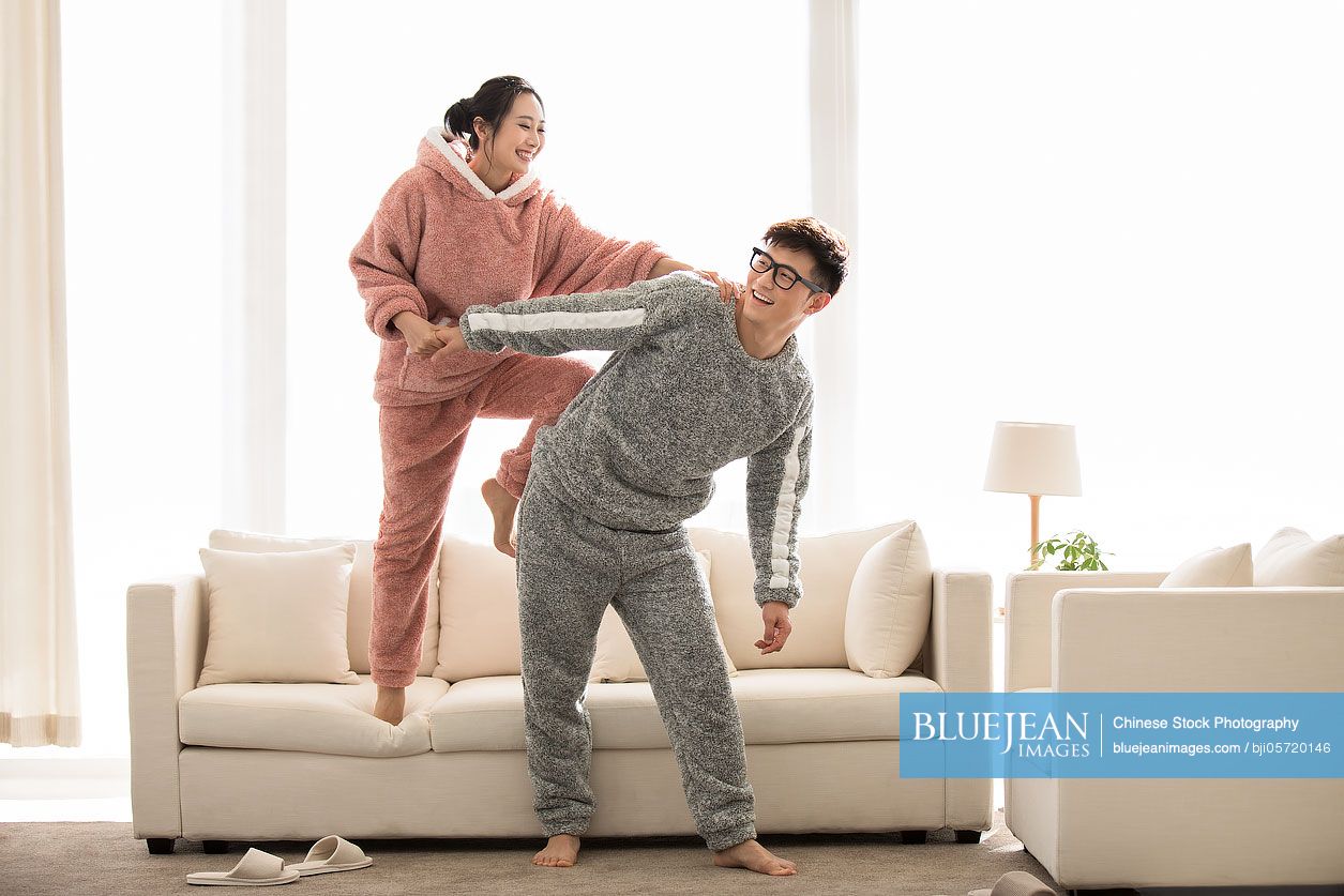 Happy young Chinese couple having fun in living room