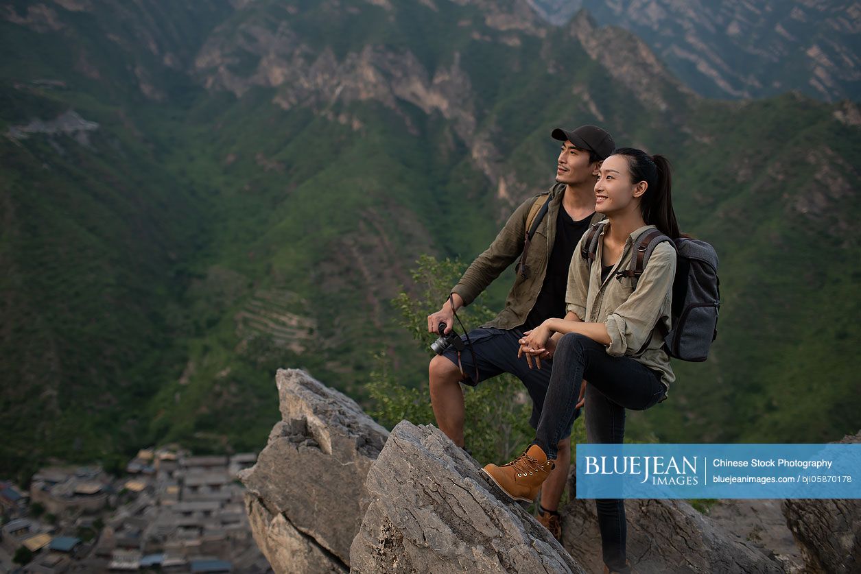 Young Chinese couple taking photos with camera outdoors