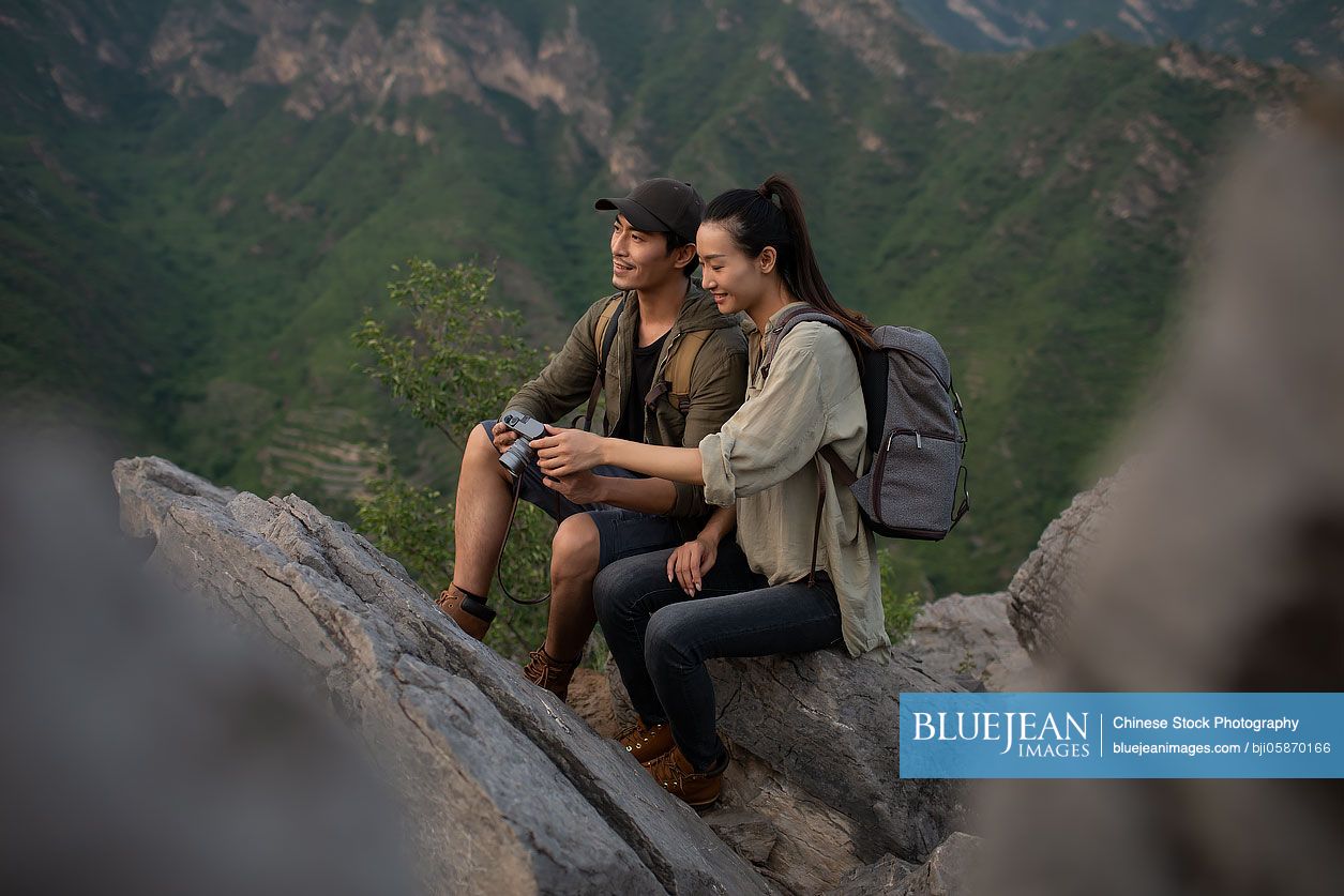 Young Chinese couple taking photos with camera outdoors