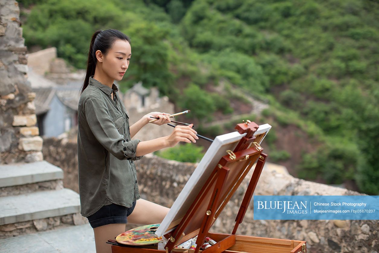 Young Chinese artist painting outdoors