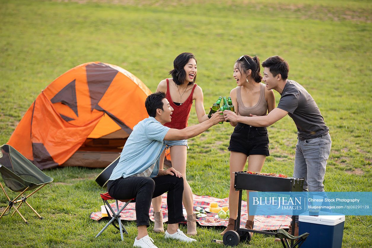 Happy young Chinese friends barbecuing outdoors
