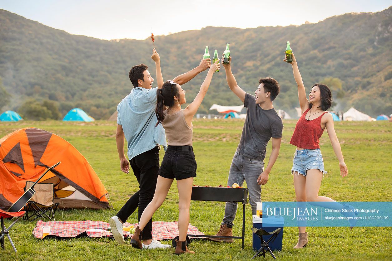Happy young Chinese friends barbecuing outdoors