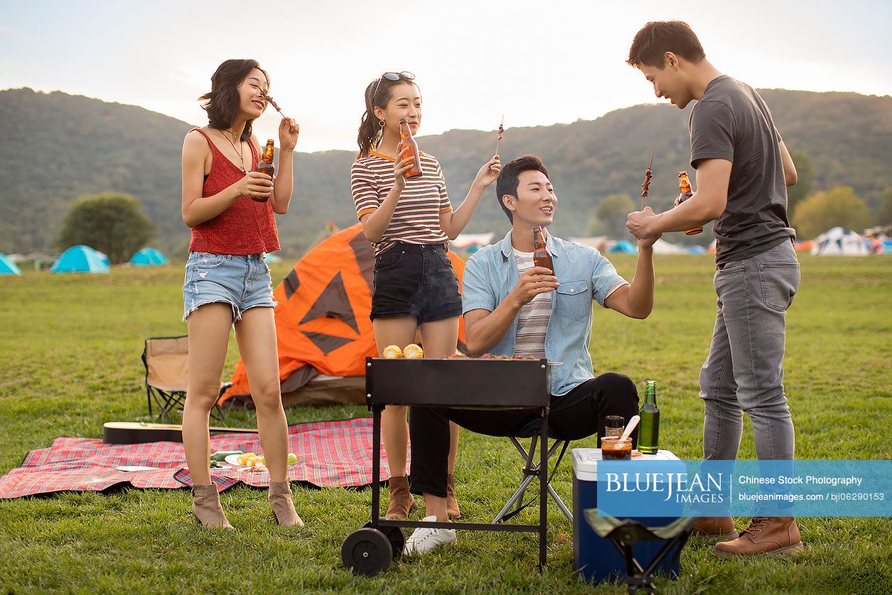 Happy young Chinese friends barbecuing outdoors