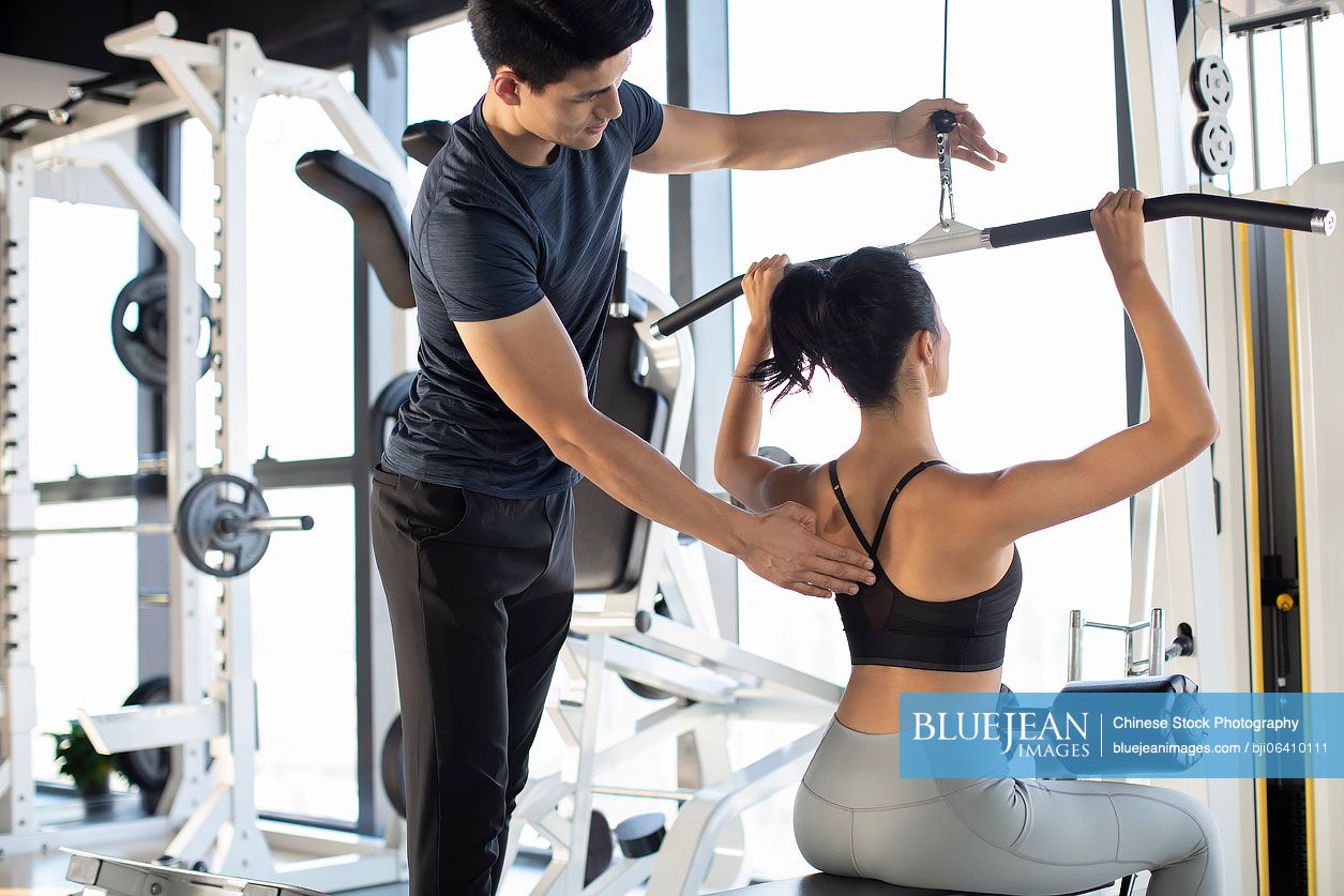 Young Chinese woman working out with personal trainer at gym