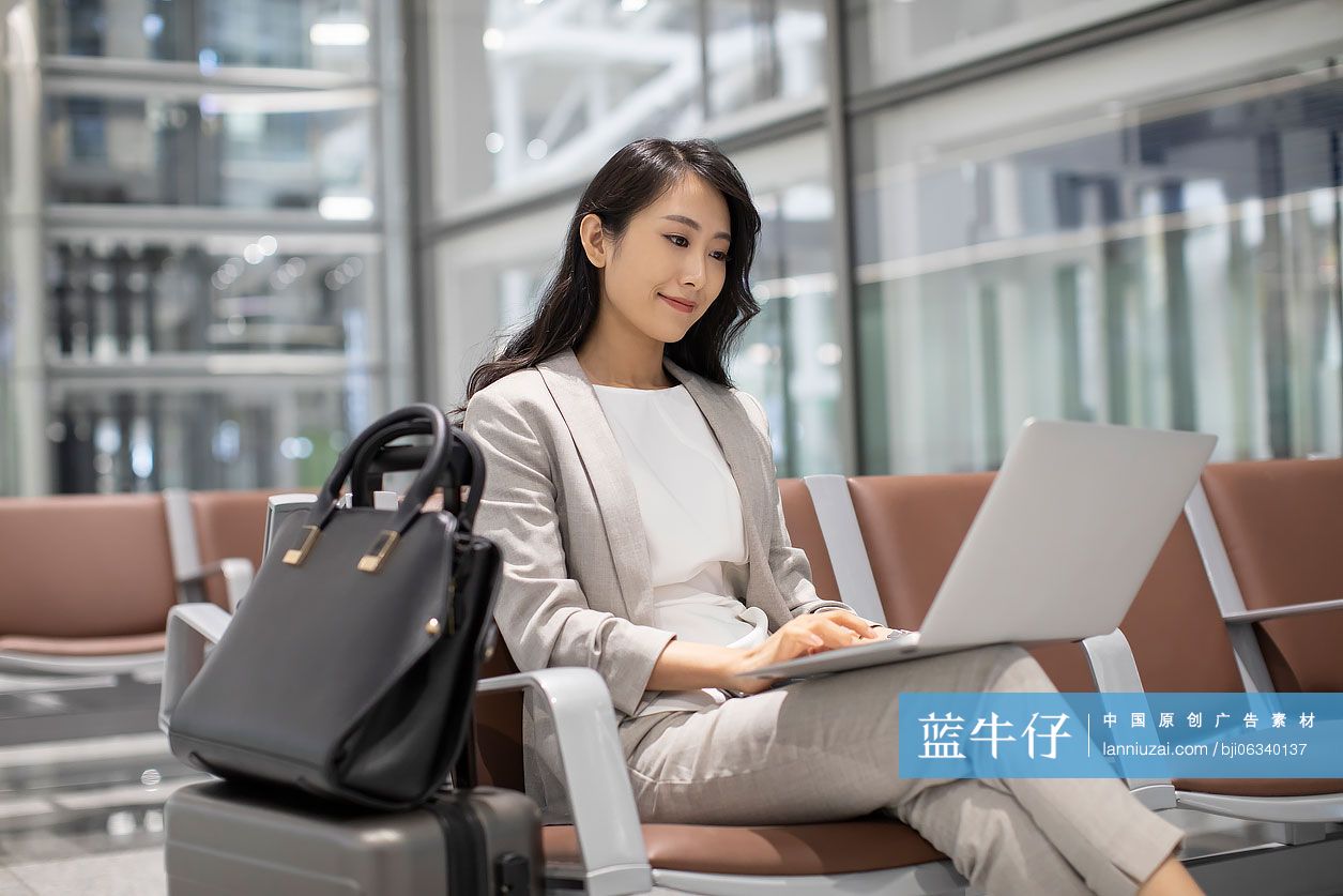 年轻商务女士在机场使用笔记本电脑