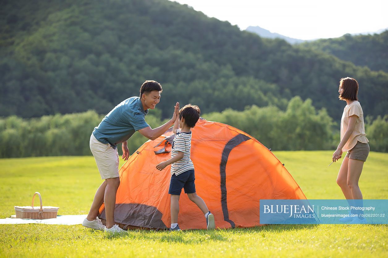 Happy young Chinese family camping outdoors