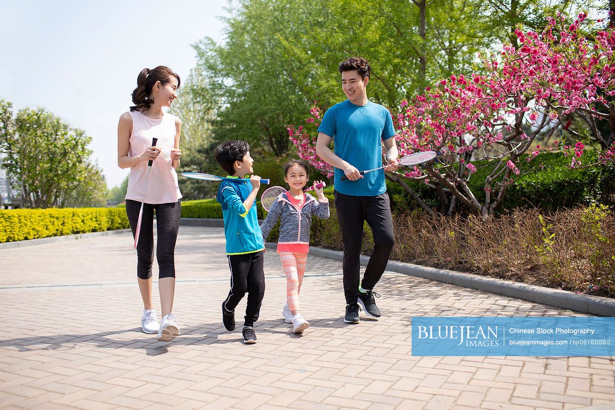 Happy young Chinese family playing badminton in park