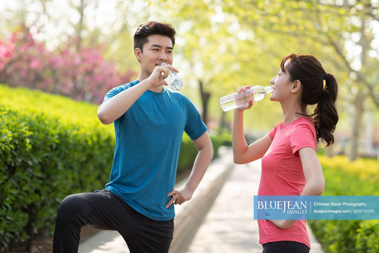 Happy young Chinese couple resting after exercising in park