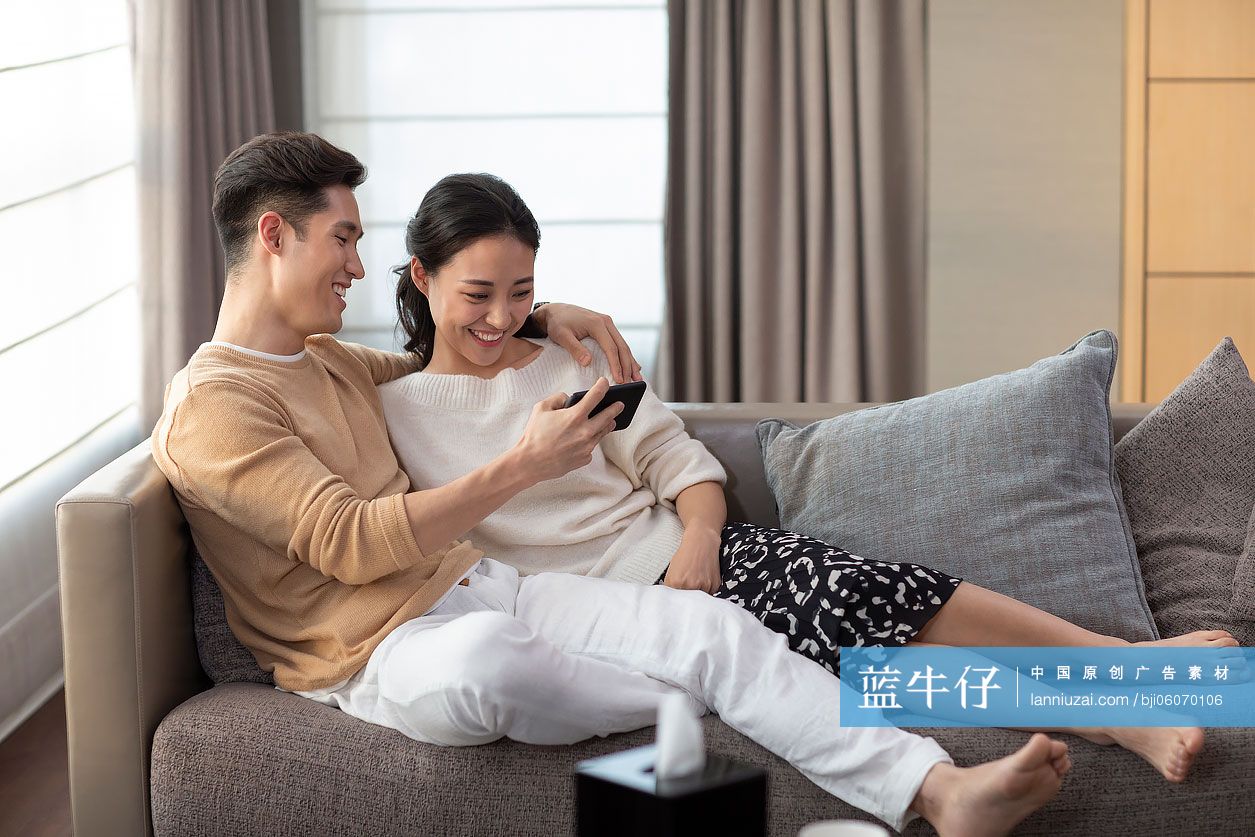 快乐的年轻情侣在客厅沙发上-蓝牛仔影像-中国原创广告影像素材