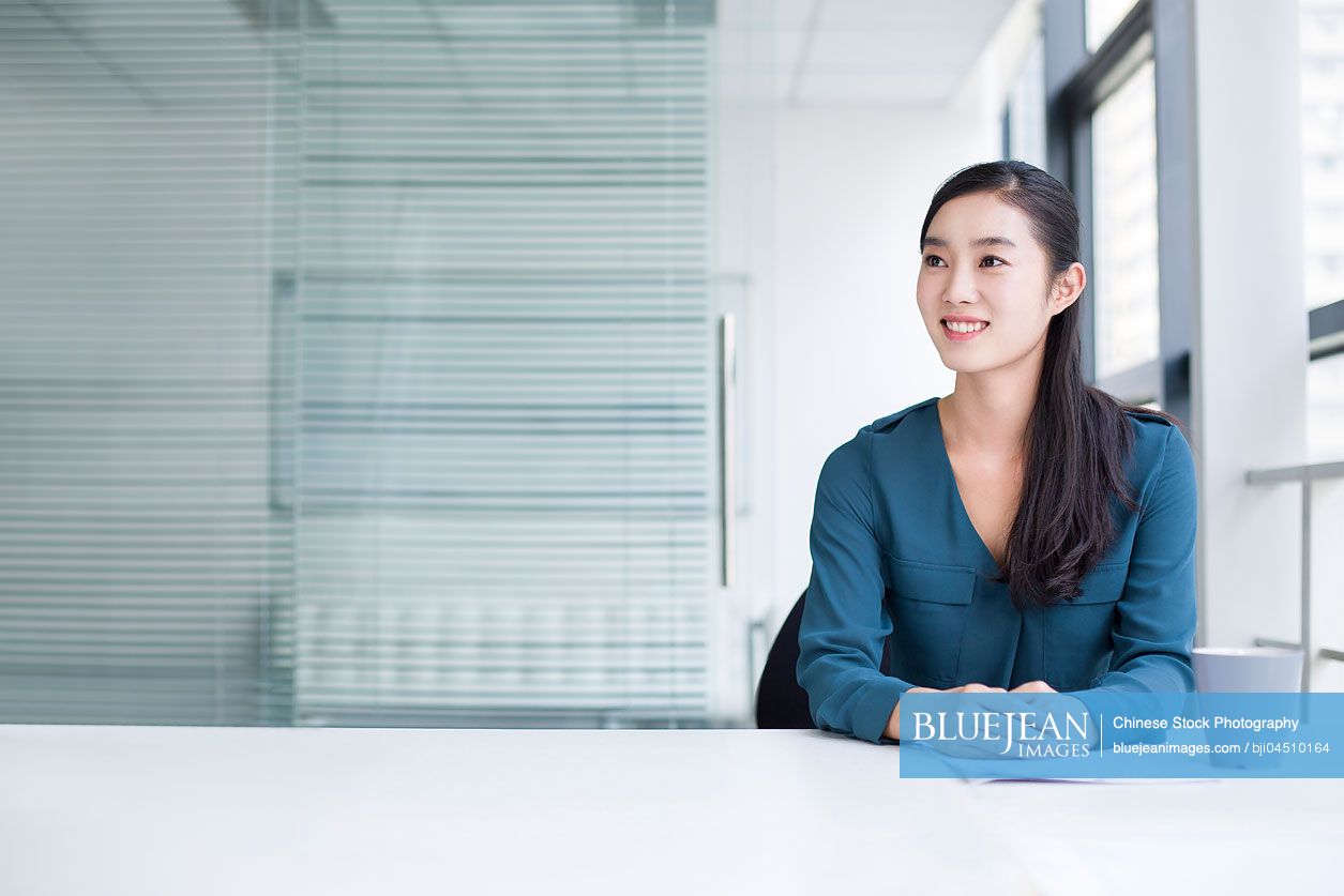 Young Chinese businesswoman thinking in office