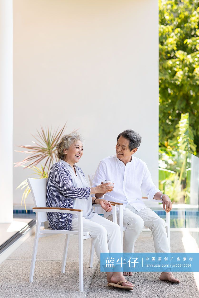 快乐的老年夫妇在阳台喝酒