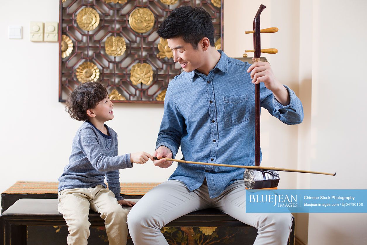 Chinese father teaching traditional musical instrument erhu